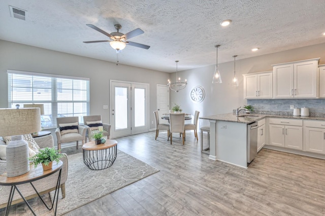 interior space with a textured ceiling, stainless steel dishwasher, pendant lighting, and white cabinetry