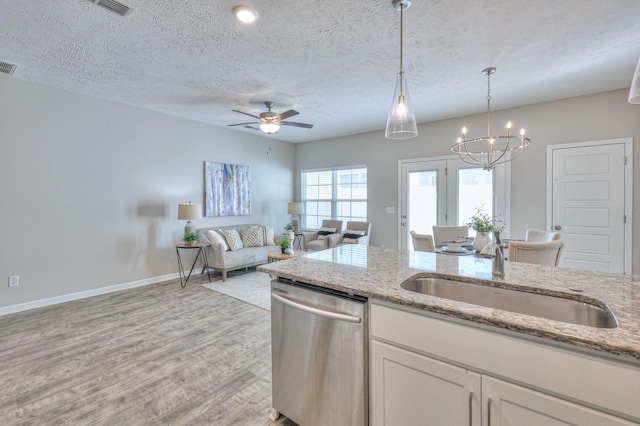 kitchen with light stone countertops, a textured ceiling, white cabinets, stainless steel dishwasher, and sink