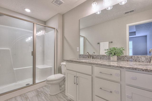 bathroom featuring toilet, vanity, a textured ceiling, and a shower with shower door