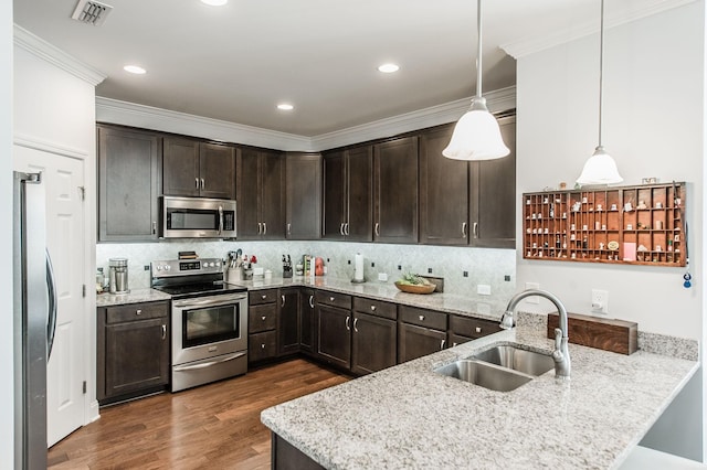 kitchen featuring light stone countertops, decorative light fixtures, stainless steel appliances, sink, and dark brown cabinetry