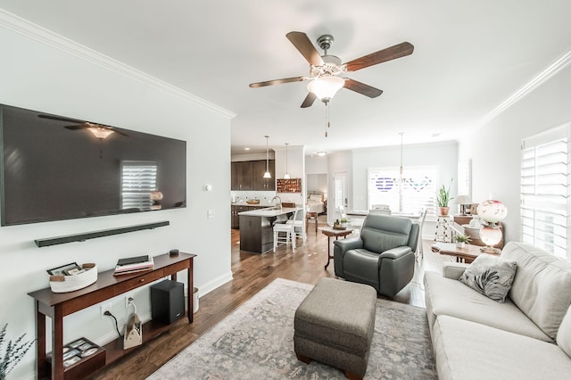 living room with ceiling fan with notable chandelier, sink, crown molding, and dark hardwood / wood-style floors