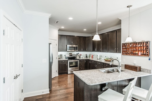 kitchen with stainless steel appliances, sink, kitchen peninsula, a breakfast bar area, and pendant lighting