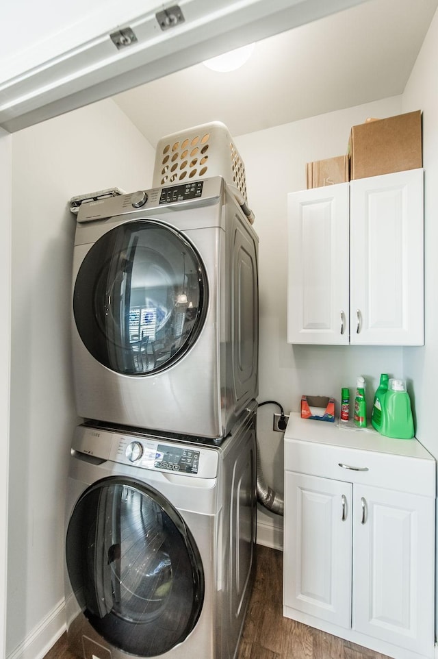 clothes washing area featuring dark wood-type flooring, cabinets, and stacked washer / dryer