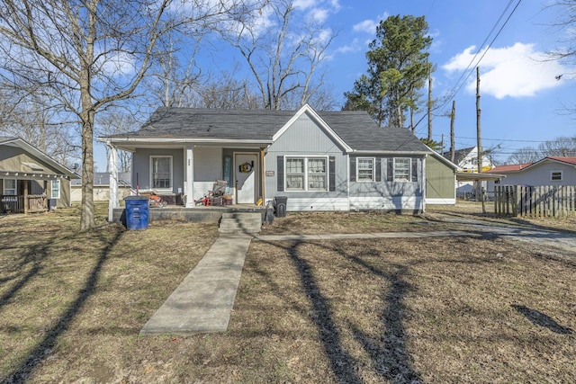 bungalow-style house featuring a carport, covered porch, and a front lawn