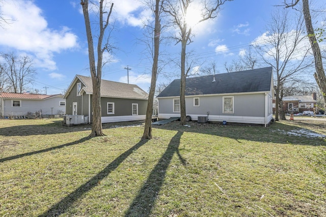 rear view of property featuring central air condition unit and a yard