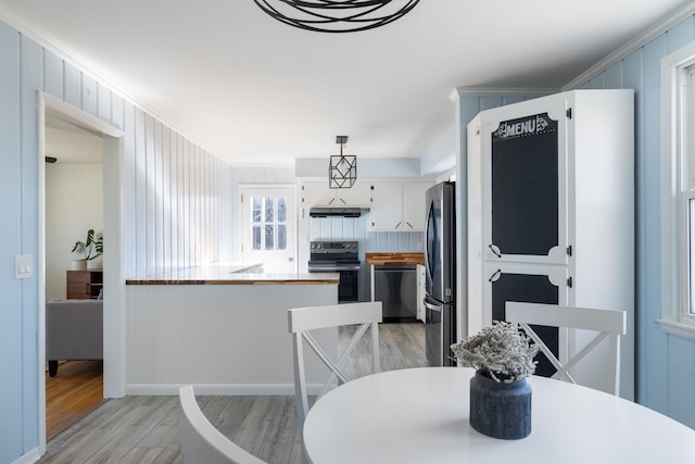 dining space featuring light wood-type flooring and crown molding