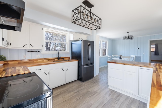 kitchen featuring stainless steel refrigerator, range with electric cooktop, wood counters, pendant lighting, and white cabinets