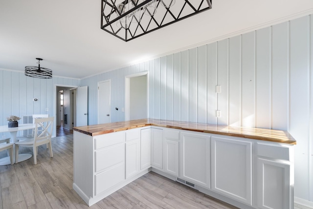 kitchen with white cabinets, an inviting chandelier, light hardwood / wood-style flooring, wooden counters, and pendant lighting