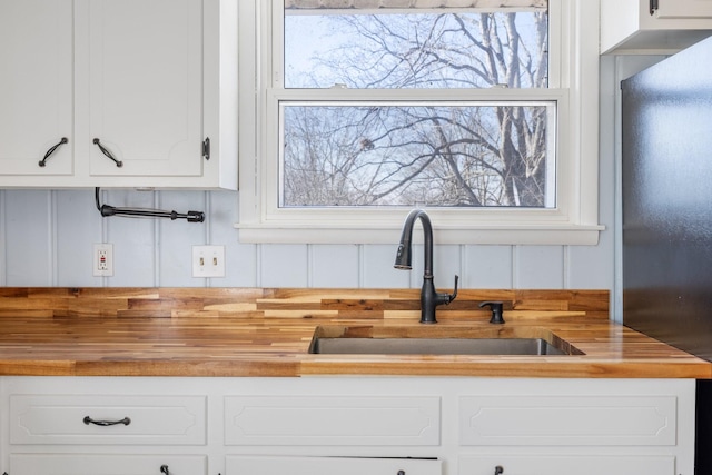 kitchen with sink, wooden counters, and white cabinets