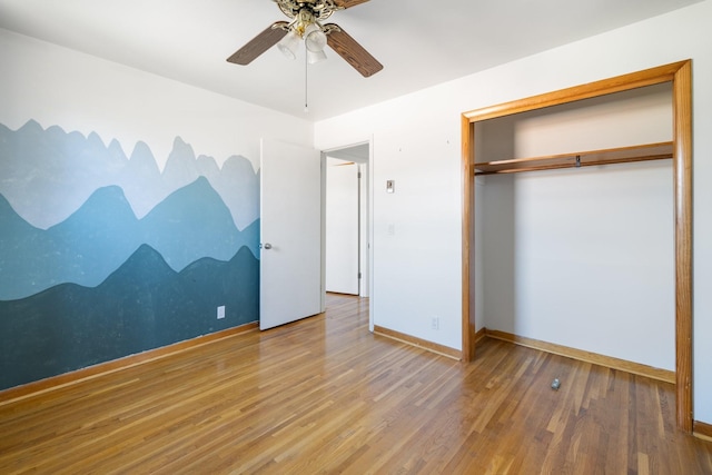 unfurnished bedroom with wood-type flooring, ceiling fan, and a closet