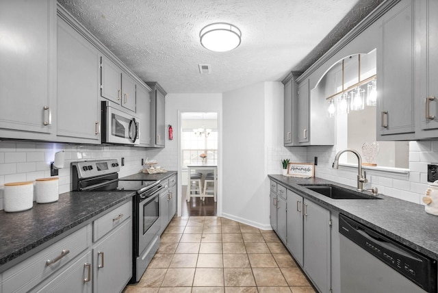 kitchen with sink, stainless steel appliances, light tile patterned flooring, and gray cabinets