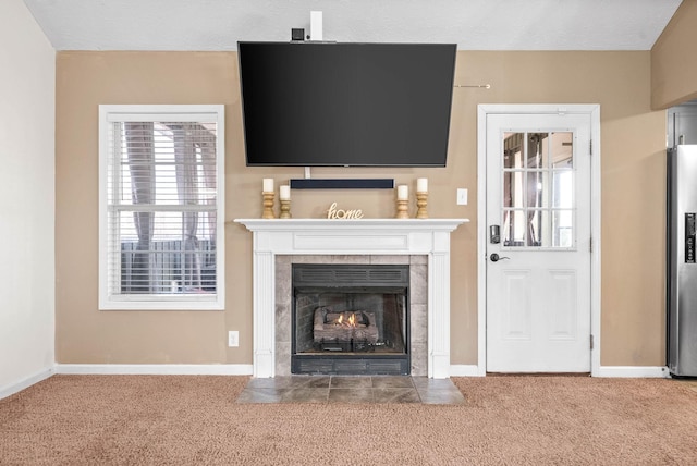 unfurnished living room featuring a tiled fireplace and carpet flooring