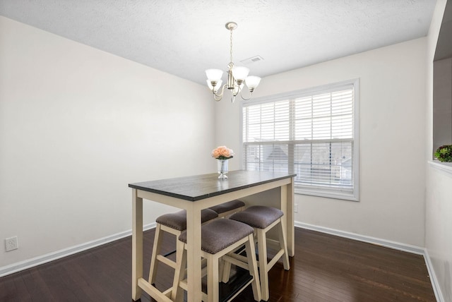 dining room featuring a textured ceiling, a notable chandelier, and dark hardwood / wood-style floors