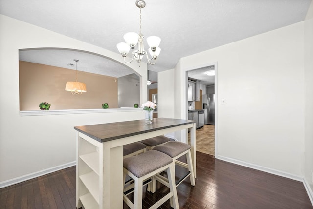 dining room with a textured ceiling, an inviting chandelier, and dark hardwood / wood-style floors