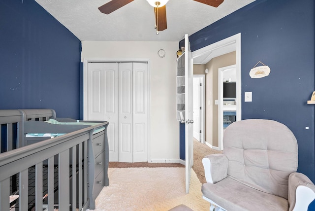 bedroom with ceiling fan, light colored carpet, a closet, and a textured ceiling