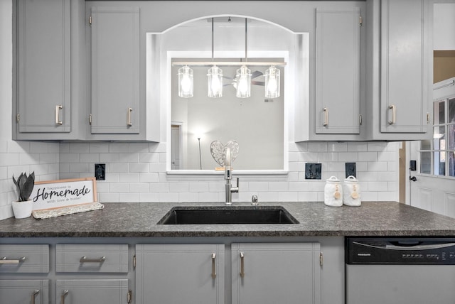 kitchen featuring sink, stainless steel dishwasher, backsplash, gray cabinets, and pendant lighting