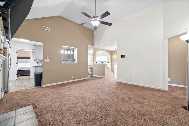 unfurnished living room featuring ceiling fan, high vaulted ceiling, and light carpet