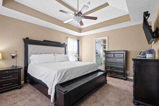 carpeted bedroom featuring a raised ceiling, ceiling fan, a textured ceiling, and connected bathroom