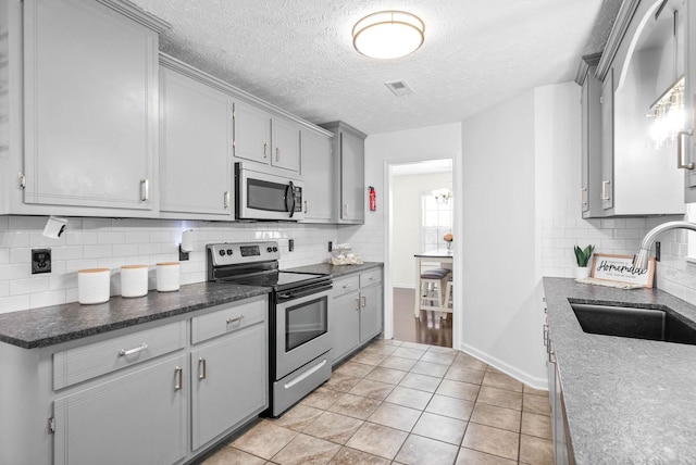 kitchen featuring sink, stainless steel appliances, gray cabinetry, and light tile patterned floors