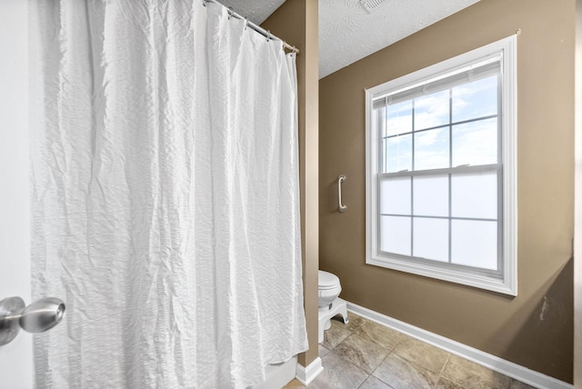 bathroom with toilet, tile patterned flooring, and a textured ceiling