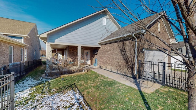 back of house featuring a lawn and covered porch