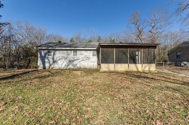 exterior space with a sunroom, a lawn, and fence