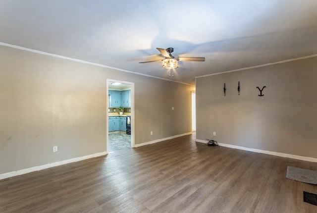 spare room with crown molding, baseboards, ceiling fan, and wood finished floors