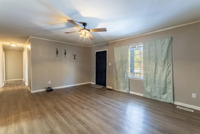 empty room with ornamental molding, visible vents, baseboards, and wood finished floors