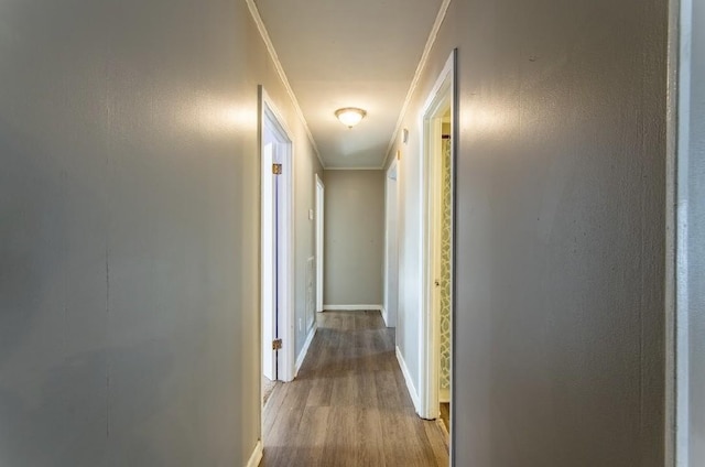 hallway with baseboards, ornamental molding, and wood finished floors