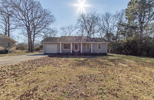 single story home featuring central air condition unit, covered porch, a garage, driveway, and a front lawn