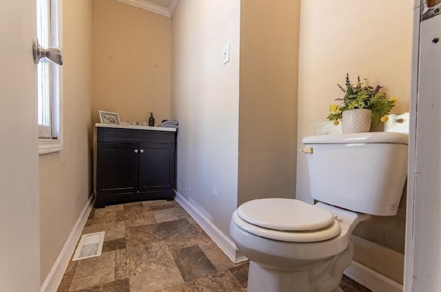 half bathroom featuring toilet, vanity, visible vents, and baseboards