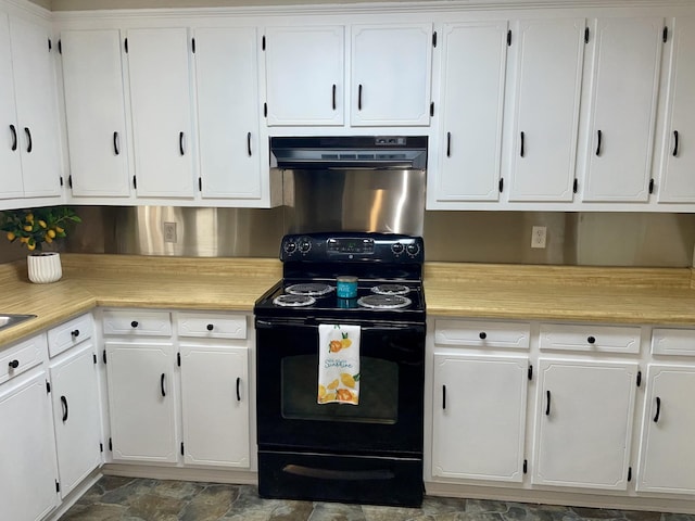 kitchen with white cabinets, stone finish flooring, light countertops, under cabinet range hood, and black range with electric cooktop