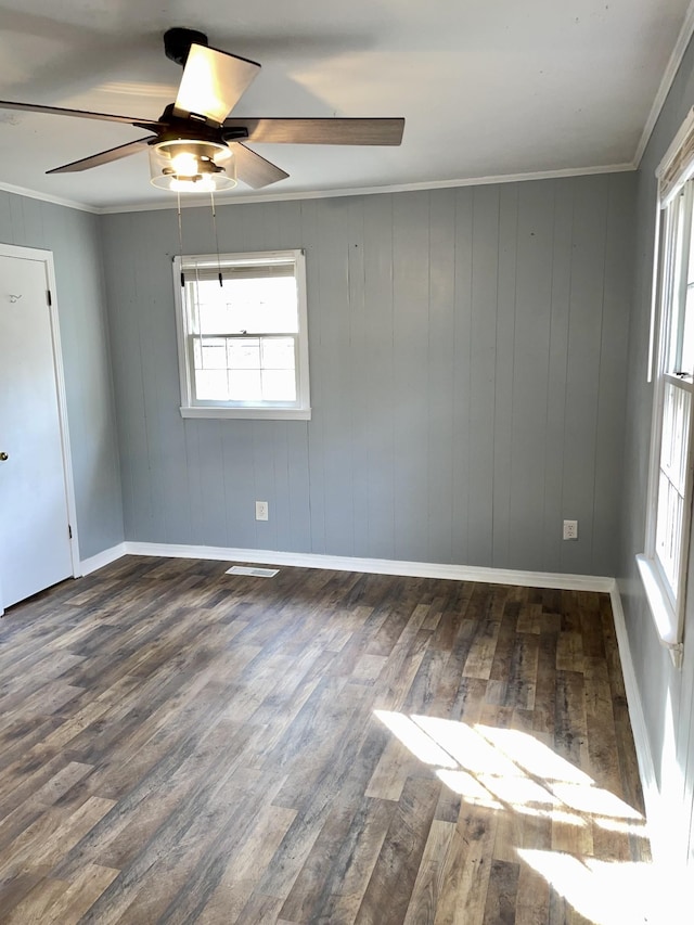 empty room featuring visible vents, crown molding, baseboards, and wood finished floors