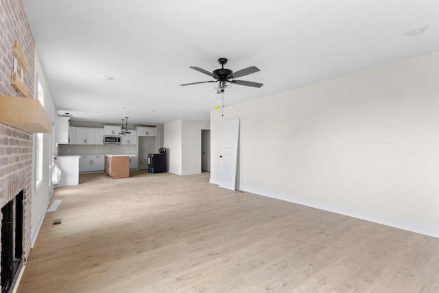 unfurnished living room featuring a fireplace, ceiling fan, plenty of natural light, and light hardwood / wood-style flooring