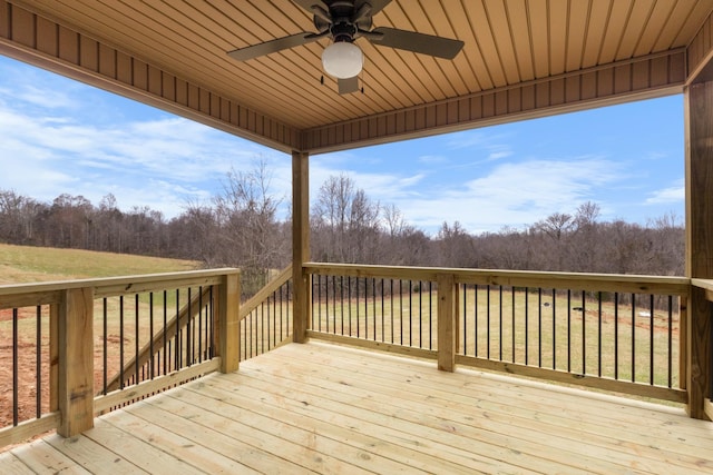 wooden terrace featuring ceiling fan and a lawn