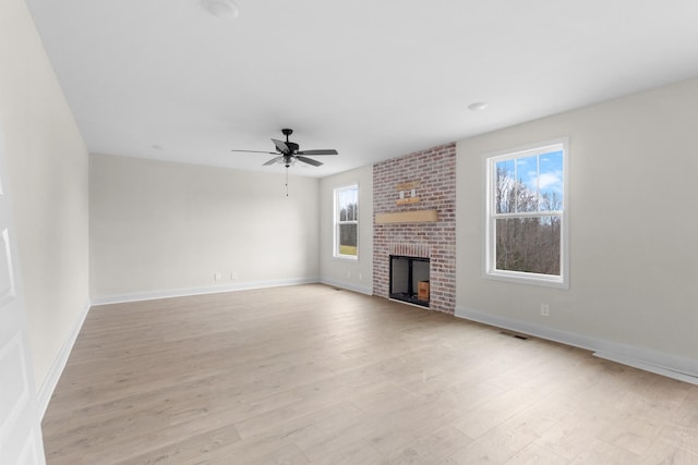 unfurnished living room with a brick fireplace, light wood-type flooring, and ceiling fan