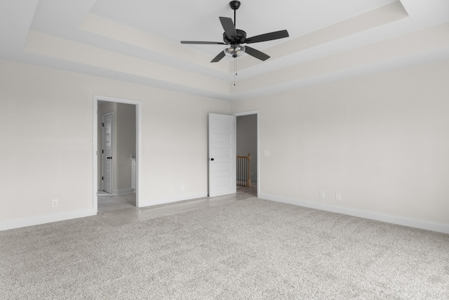 carpeted spare room featuring ceiling fan and a tray ceiling