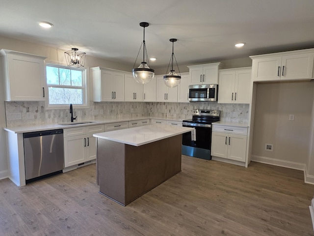 kitchen featuring backsplash, white cabinets, stainless steel appliances, a sink, and wood finished floors