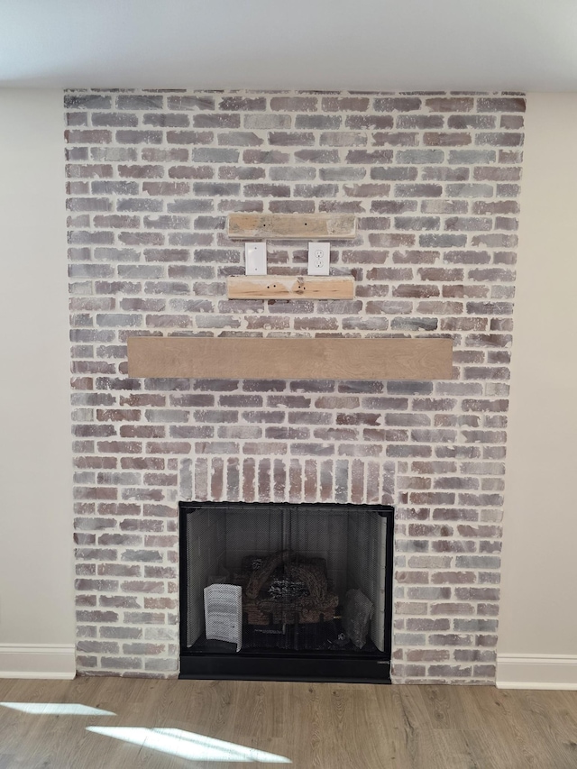 room details with baseboards, wood finished floors, and a brick fireplace