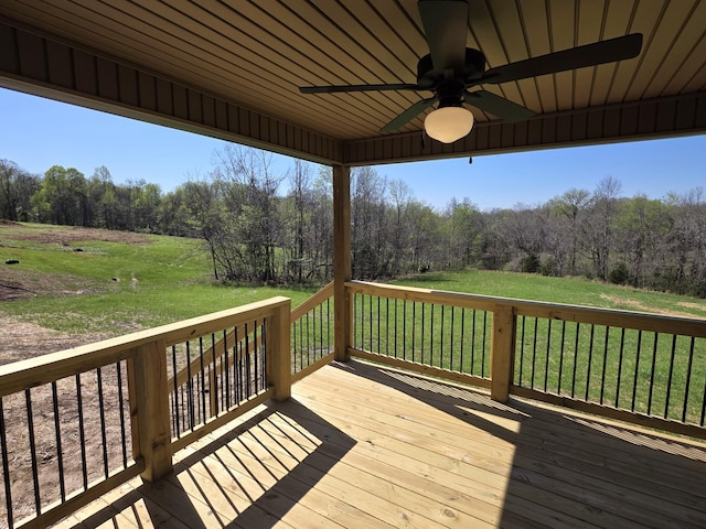 wooden terrace featuring a forest view, ceiling fan, and a lawn