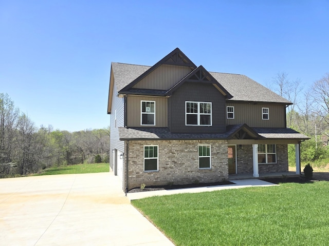 craftsman-style home with a garage, a front yard, brick siding, a shingled roof, and concrete driveway