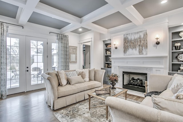 living room with beamed ceiling, french doors, built in features, light hardwood / wood-style flooring, and coffered ceiling