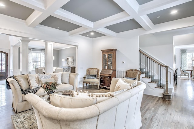 living room with coffered ceiling, hardwood / wood-style floors, ornate columns, crown molding, and beam ceiling