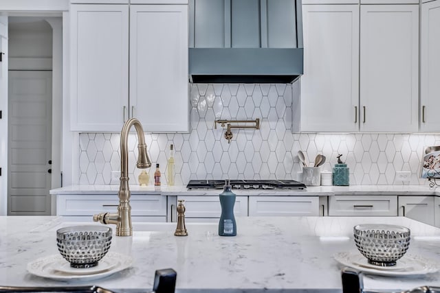 kitchen featuring stainless steel gas stovetop, tasteful backsplash, and light stone counters