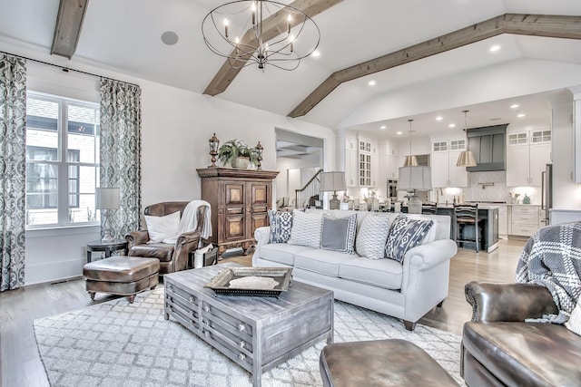 living room with a notable chandelier, light wood-type flooring, lofted ceiling with beams, and a wealth of natural light