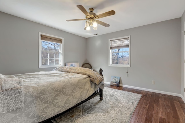 bedroom with ceiling fan, dark hardwood / wood-style flooring, and multiple windows