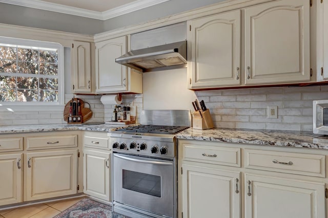 kitchen featuring light stone countertops, wall chimney exhaust hood, decorative backsplash, stainless steel gas stove, and ornamental molding