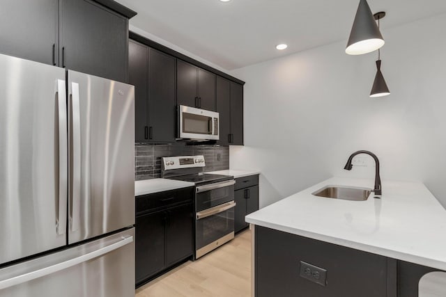 kitchen with pendant lighting, sink, light hardwood / wood-style flooring, stainless steel appliances, and decorative backsplash