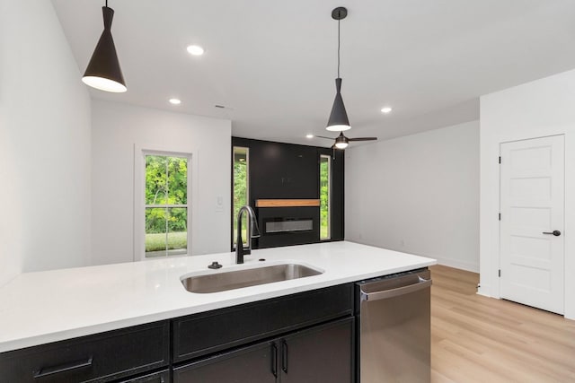 kitchen with stainless steel dishwasher, sink, pendant lighting, and light wood-type flooring