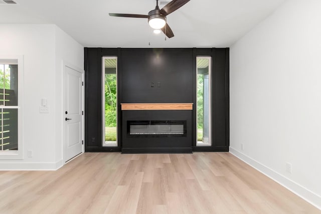 entryway with a fireplace, light wood-type flooring, and ceiling fan